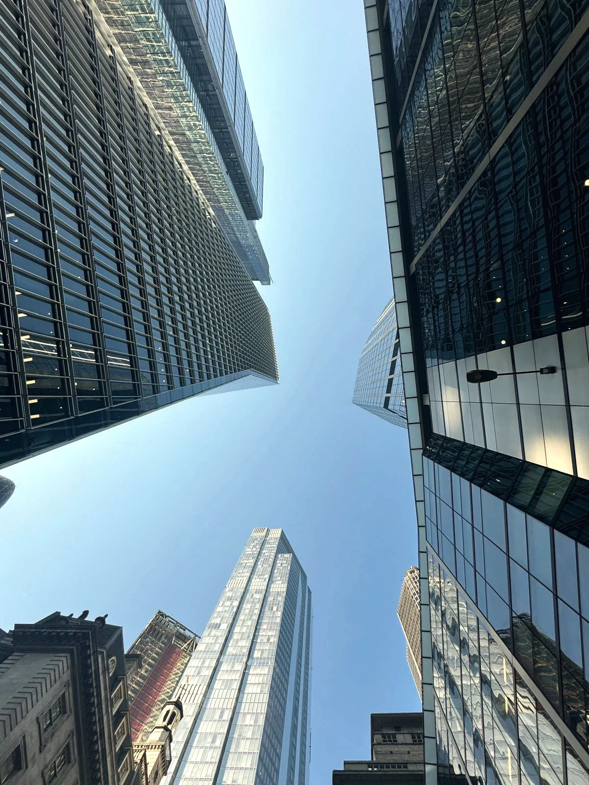 Looking straight up between glass towers in the City of London