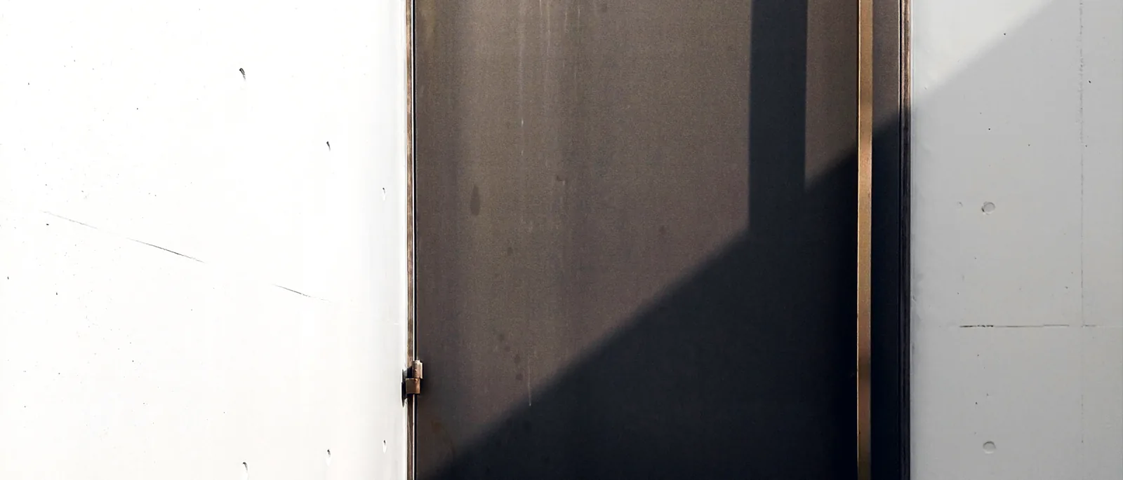 A stainless-steel fire door with an overhead closer set into a concrete stairwell landing beside a handrail