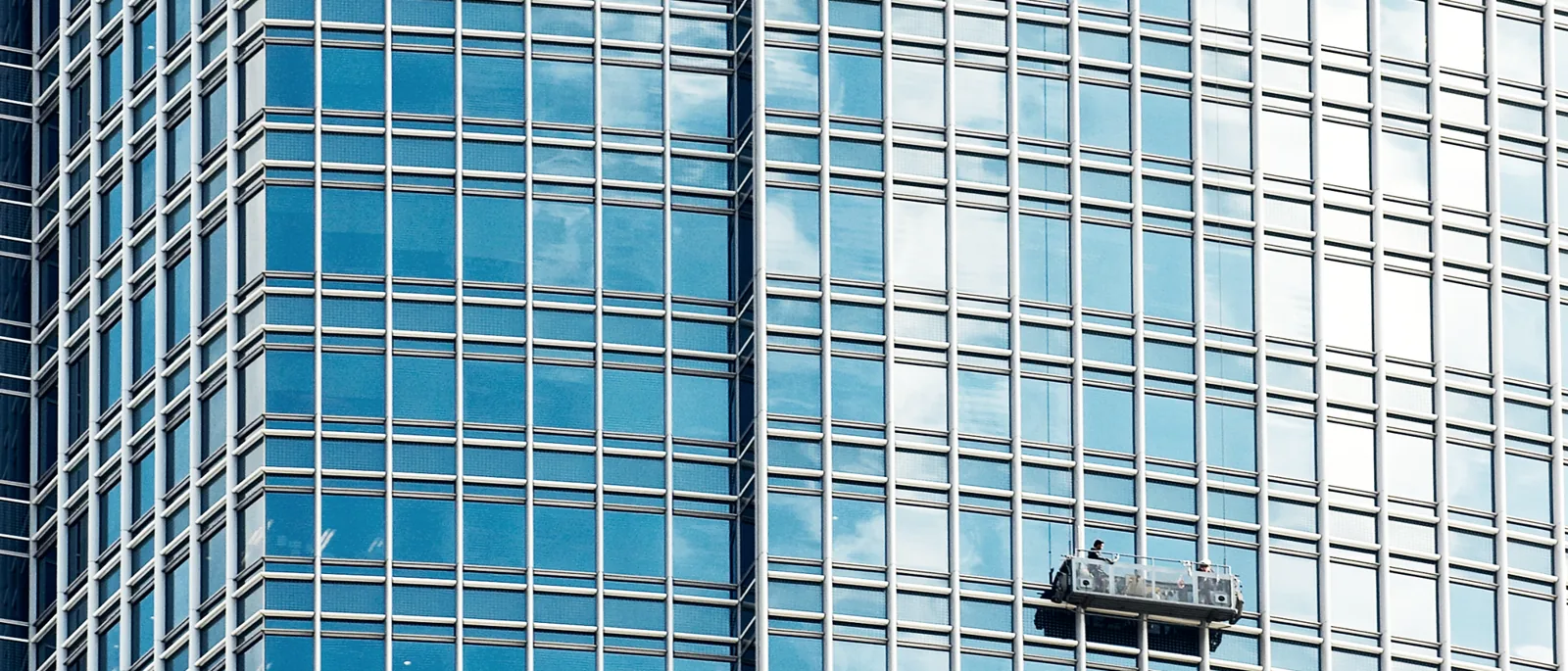 A glass office tower facade with a maintenance access cradle