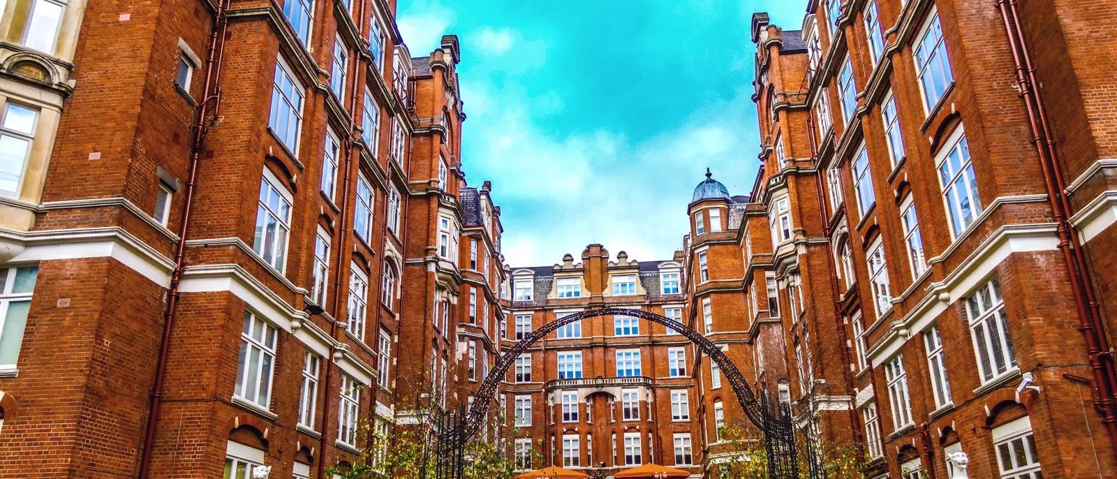 Grand red-brick mansion blocks around a landscaped courtyard with an ornamental archway