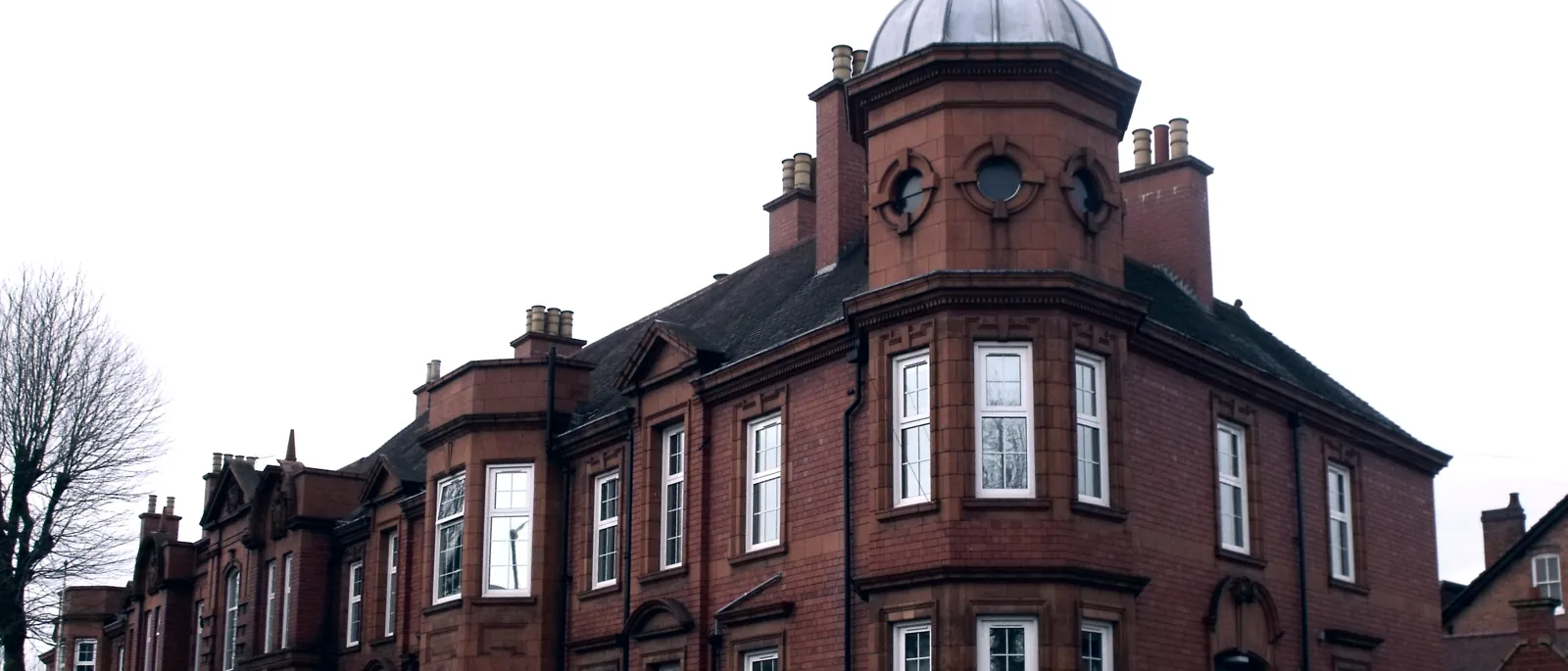 A red-brick Victorian police station with an octagonal corner turret and domed cupola
