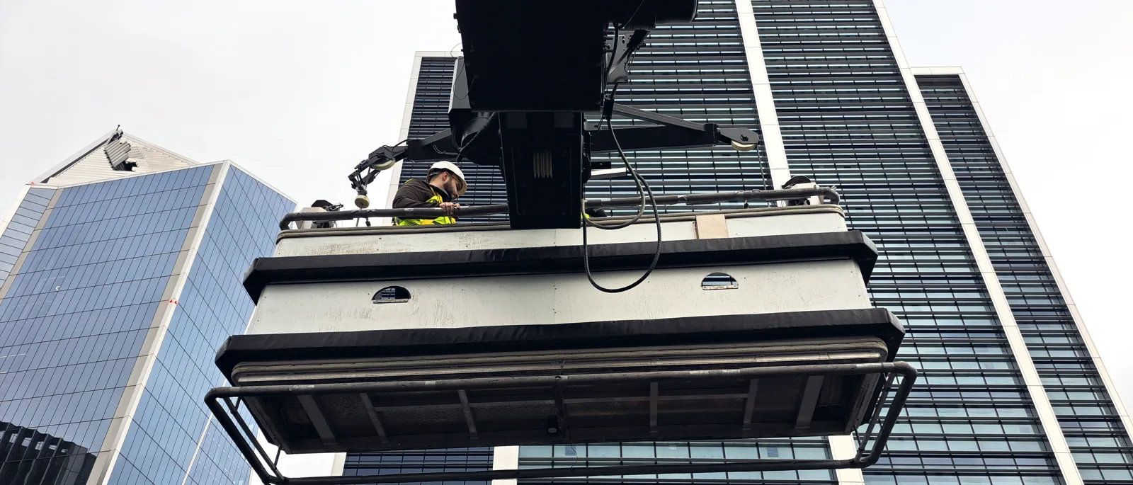 A building maintenance cradle suspended against a glass tower on Leadenhall Street