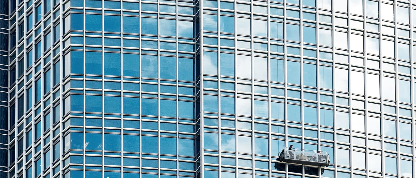 A distant glass tower elevation with a small maintenance access cradle